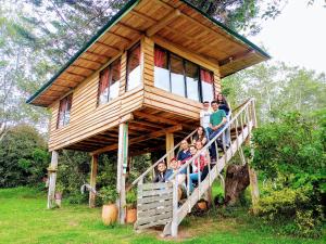 eine Gruppe von Menschen, die auf der Treppe eines Baumhauses sitzen in der Unterkunft Monte Verde Cabañas y Camping in Arcabuco