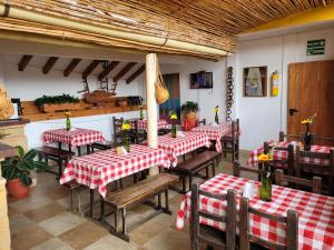 un restaurante con mesas y sillas rojas y blancas a cuadros en Casa Cantabria Hotel, en Villa de Leyva