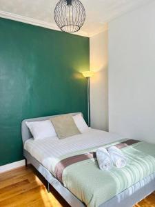a bed in a room with a green wall at Elegant House in Stratford in London