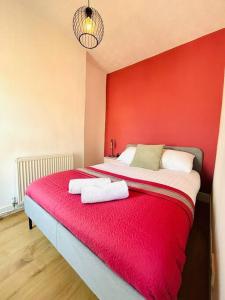 a red room with a bed with two towels on it at Elegant House in Stratford in London