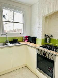 uma cozinha com um lavatório e um fogão forno superior em Elegant House in Stratford em Londres