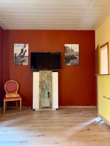 Il comprend un salon doté d'une télévision à écran plat sur un mur rouge. dans l'établissement Kuckucksnest, à Bielefeld