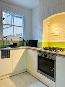 uma cozinha com armários brancos e um forno com placa de fogão em Elegant House in Stratford em Londres