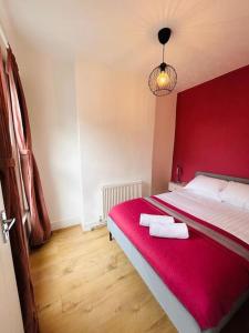 a bedroom with a red bed with two towels on it at Elegant House in Stratford in London
