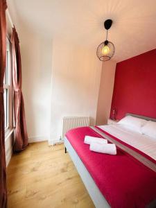 a bedroom with a red bed with two towels on it at Elegant House in Stratford in London