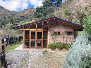 una pequeña casa con puertas de cristal y una montaña en Cabaña La Guaranga, en Loja