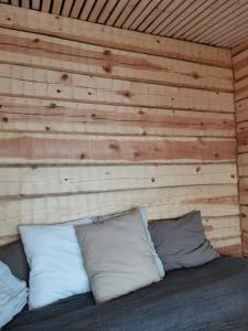 a bedroom with a wooden wall with pillows on a bed at Wilderness Cabin Onnela in Rovaniemi