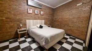1 dormitorio con cama y pared de ladrillo en Pequeña Allegra en San Juan