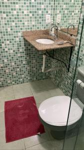 a bathroom with a toilet and a sink and a red rug at casa de Luciana - Lençóis in Lençóis