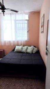 a bedroom with a large bed with a window at Quarto em apt compartilhado com estacionamento incluso in Niterói
