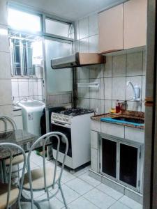 a kitchen with a stove and a table with chairs at Quarto em apt compartilhado com estacionamento incluso in Niterói