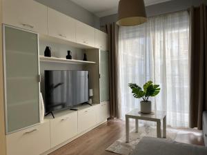 ein Wohnzimmer mit einem TV und einer Topfpflanze in der Unterkunft Garbary 100 CITY CENTER Apartment, free parking, self check-in 24h in Posen