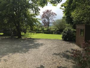 a gravel driveway with a fence and a grass field at Barnhaven, Lake District National Park in Brigsteer