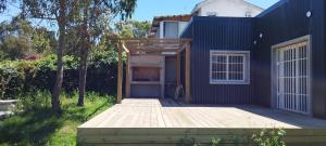 una casa con una terraza de madera frente a ella en Casa Atlántida 2 Dorm. Deck con Parrillero, 3 de Playa Mansa, en Atlántida