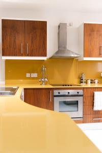 a yellow kitchen with wooden cabinets and a sink at Modern Central 2BR Flat in Valletta in Valletta
