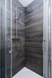 a shower in a bathroom with a wooden wall at Horský apartmán Temari 10 Klínovec in Loučná pod Klínovcem