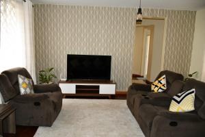 een woonkamer met 2 banken en een flatscreen-tv bij Stawi Apartment in Nairobi