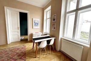 Habitación con mesa, sillas y ventanas. en Ruhige & große Altbauwohnung 7min zum Zentrum, en Viena