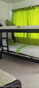 2 Etagenbetten in einem Zimmer mit grünem Vorhang in der Unterkunft Hospedaje los almendros in San Antero