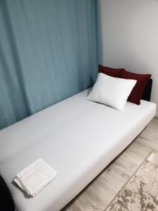 Una cama blanca con almohadas rojas y blancas. en Budget Stay Guest House, en Kosovo Polje