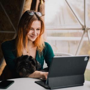 een vrouw met een hond die naar een laptop kijkt bij Готель Еко Сфера 