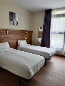 a hotel room with two beds and a window at Apartahotel Golden Alcalá in Alcalá de Henares