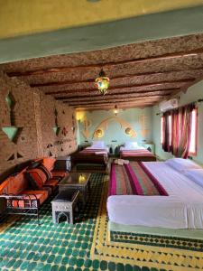 a bedroom with two beds and a couch in it at Hotel ksar merzouga in Merzouga