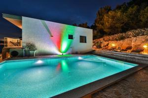 a swimming pool in front of a house at night at Villa Regina with heated pool and sea view in Marina