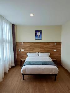 - une chambre avec un grand lit et une tête de lit en bois dans l'établissement Apartahotel Golden Alcalá, à Alcalá de Henares