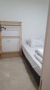 1 cama con sábanas blancas y almohadas en una habitación en מקום מקסים בפתח תקווה, en Petaj Tikva