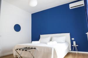 ein Schlafzimmer mit einer blauen Wand und einem weißen Bett in der Unterkunft Concept Apartment in Belpasso