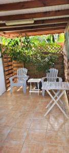 - 2 chaises blanches et une table sur la terrasse dans l'établissement Le jacquier, à Goyave