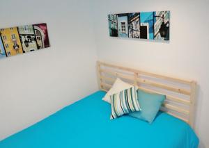 um quarto com uma cama azul com duas fotografias na parede em Apartamento Embaixador Mateus em Lisboa