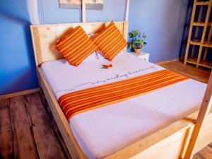 ein Holzbett mit zwei orangenen Kissen darauf in der Unterkunft Arusha Jua home in Arusha