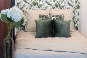 een bed met vier kussens en een vaas met bloemen bij Le charmant Yin-Yang studio proche de Paris in Montrouge