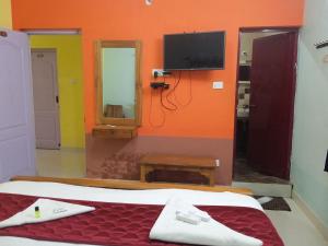 a bedroom with a bed and a tv on the wall at J J HOMES in Ooty