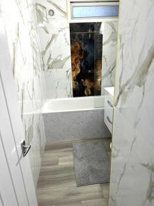 un bagno bianco con vasca e lavandino di Stylish Apartment At Carlton Grove a Londra