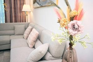sala de estar con sofá y jarrón con flores en Mariana Luxurious 2BR Apartment, en Abu Dabi