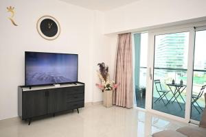 sala de estar con TV de pantalla plana y balcón en Mariana Luxurious 2BR Apartment, en Abu Dabi