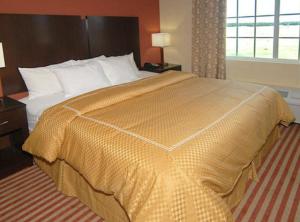 a bed in a hotel room with a yellow bedspread at Hometown Executive Suites in Bridgeport