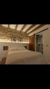 1 dormitorio con 1 cama grande y pared de piedra en MEDITERRÀNIA RURAL, en Cabanes
