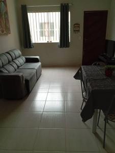 ein Wohnzimmer mit einem Sofa und einem Tisch in der Unterkunft Apartamento aconchegante in Rio das Ostras