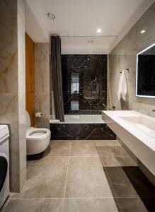 a bathroom with a toilet and a sink and a tub at Deluxe Apartment in Tashkent +41 photos