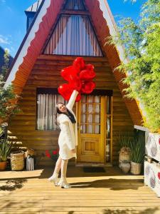 a girl holding a bunch of red balloons in front of a house at Suítes no Chalé in Campos do Jordão