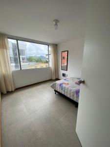 - une chambre avec un lit et une grande fenêtre dans l'établissement Apartamento Belen, à Manizales