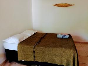 um quarto com uma cama com um cobertor castanho em Caiçaras Búzios em Búzios