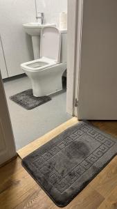 a bathroom with a toilet and a door with a rug at Large 3 Bed Apt close to city, OVO Hydro and Ibrox Stadium in Glasgow