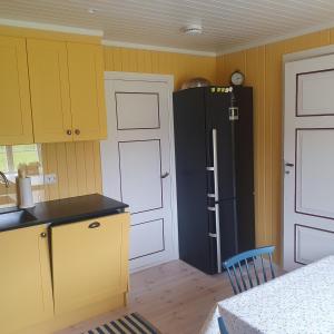 eine Küche mit gelben Schränken und einem schwarzen Kühlschrank in der Unterkunft Brekkveien 81-meget sentral hytte,15 min å gå til Røros sentrum in Røros
