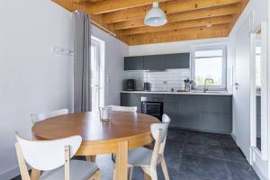 a kitchen with a wooden table and white chairs at Zachodni Wiatr - Dom Fok in Białogóra +21 photos
