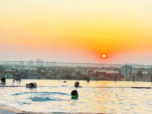 grupa ludzi w basenie o zachodzie słońca w obiekcie QMP - Friendly House Ecopark w mieście HÆ°ng YÃªn